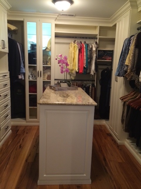 Mid-sized traditional gender-neutral walk-in wardrobe in New York with raised-panel cabinets, medium hardwood floors and white cabinets.