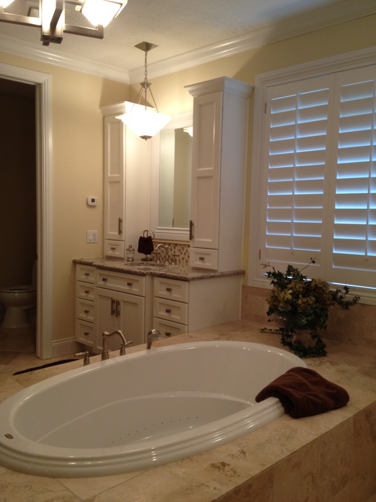 Mid-sized traditional master bathroom in Salt Lake City with white cabinets, a drop-in tub, shaker cabinets, medium hardwood floors, beige tile, brown tile, white tile, stone tile, granite benchtops, a two-piece toilet, yellow walls and an undermount sink.