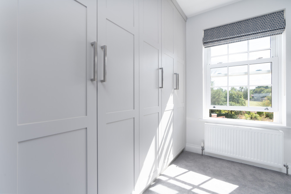 Idée de décoration pour une armoire encastrée design de taille moyenne et neutre avec un placard à porte shaker, des portes de placard grises, moquette et un sol gris.