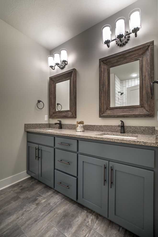 Photo of an industrial 3/4 bathroom in Omaha with shaker cabinets, an alcove shower, a two-piece toilet, subway tile, porcelain floors, an undermount sink, quartzite benchtops and a shower curtain.