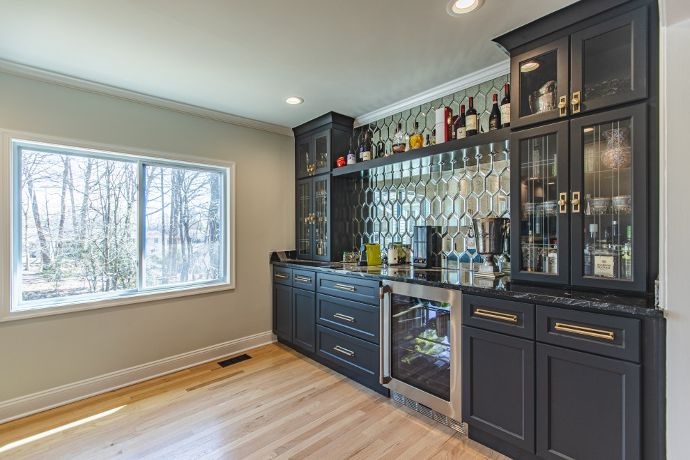 Inspiration for a mid-sized contemporary single-wall home bar in DC Metro with no sink, recessed-panel cabinets, dark wood cabinets, marble benchtops, multi-coloured splashback, glass tile splashback, medium hardwood floors, beige floor and black benchtop.