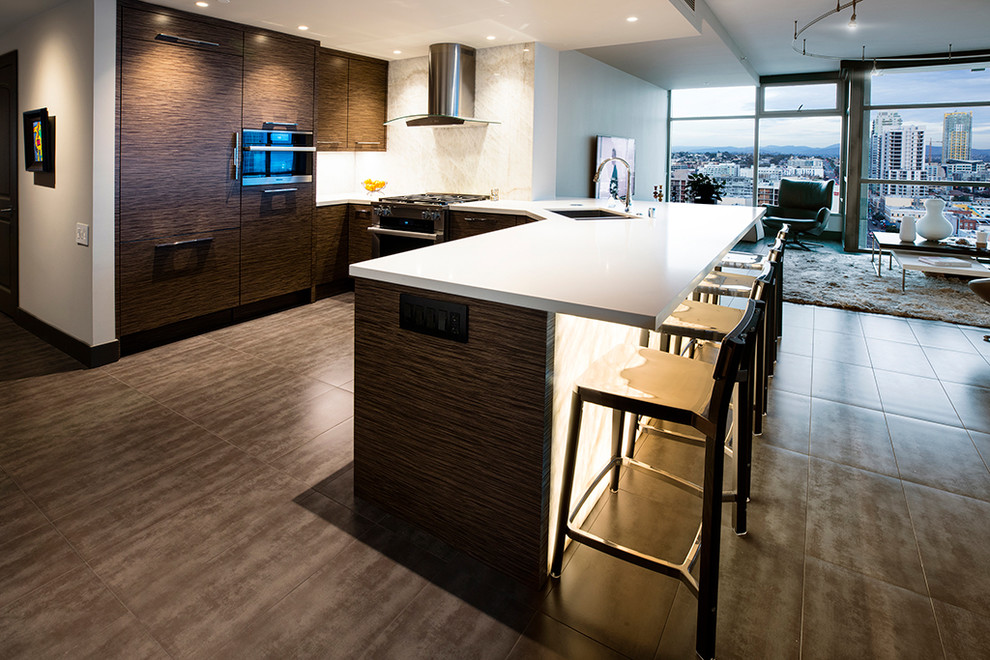 Photo of a mid-sized modern l-shaped open plan kitchen in San Diego with flat-panel cabinets, white splashback, stone slab splashback, panelled appliances, with island, a single-bowl sink, brown cabinets, onyx benchtops, porcelain floors and beige floor.