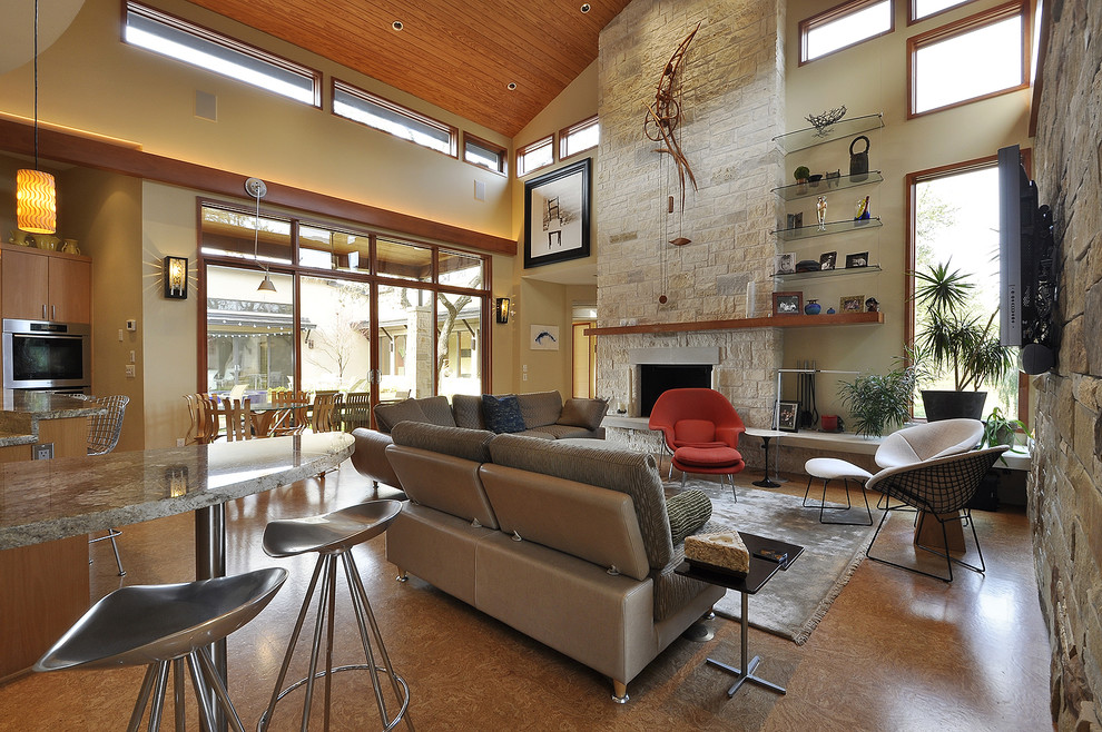 This is an example of a contemporary living room in Austin with cork floors and a stone fireplace surround.