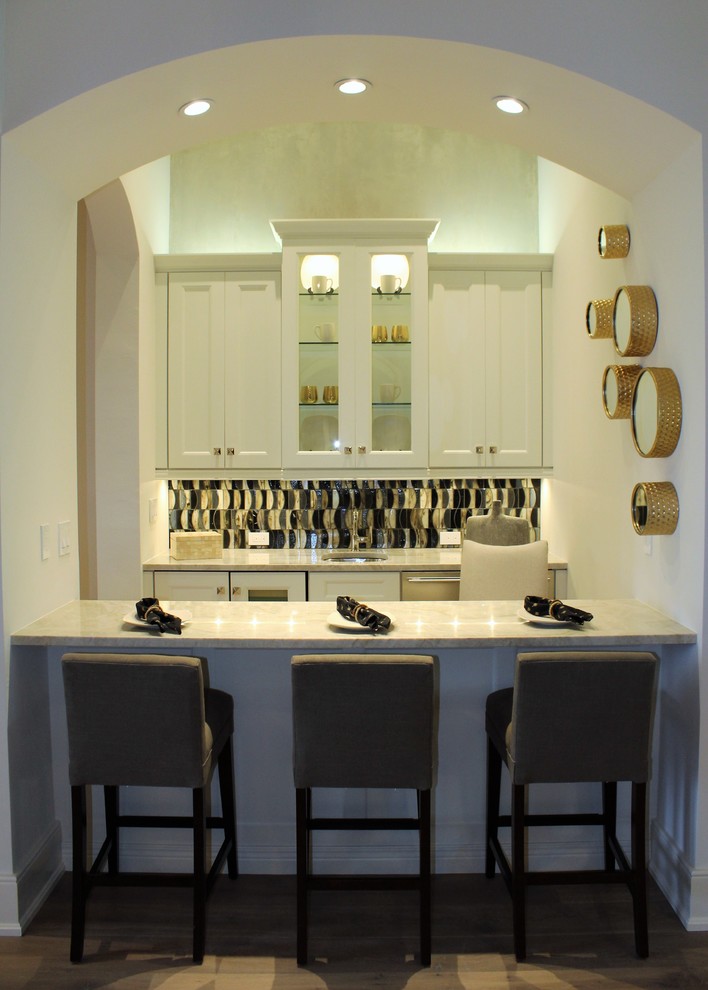 Inspiration for a mid-sized transitional galley medium tone wood floor enclosed kitchen remodel in Tampa with shaker cabinets, white cabinets, quartzite countertops, multicolored backsplash, glass sheet backsplash and no island