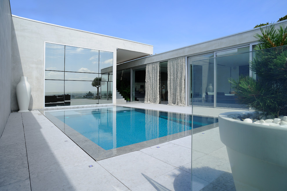 Large contemporary rooftop rectangular infinity pool in Lyon with natural stone pavers.