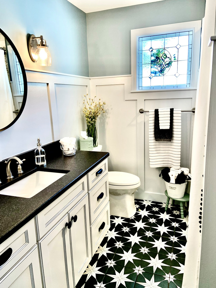 Cette image montre une petite salle de bain traditionnelle pour enfant avec un placard avec porte à panneau encastré, des portes de placard blanches, une baignoire en alcôve, un combiné douche/baignoire, WC séparés, un carrelage bleu, du carrelage en marbre, un mur bleu, un sol en carrelage de porcelaine, un lavabo encastré, un plan de toilette en granite, un sol noir, une cabine de douche avec un rideau, un plan de toilette noir, meuble simple vasque, meuble-lavabo encastré et boiseries.