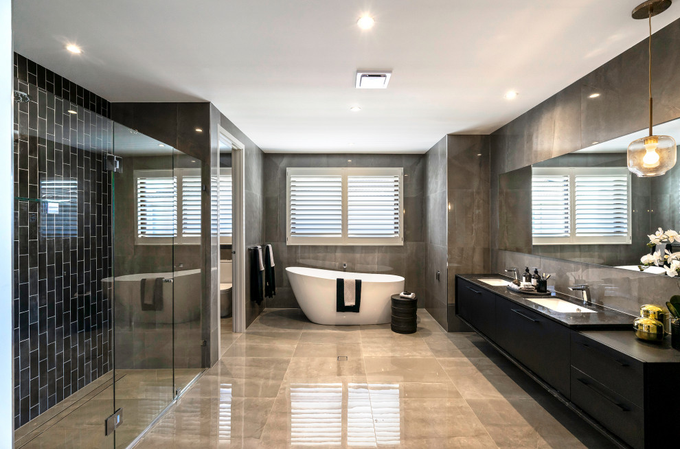 Contemporary bathroom in Sydney with flat-panel cabinets, black cabinets, a freestanding tub, an alcove shower, gray tile, an undermount sink, grey floor, a hinged shower door, black benchtops, an enclosed toilet, a double vanity and a floating vanity.