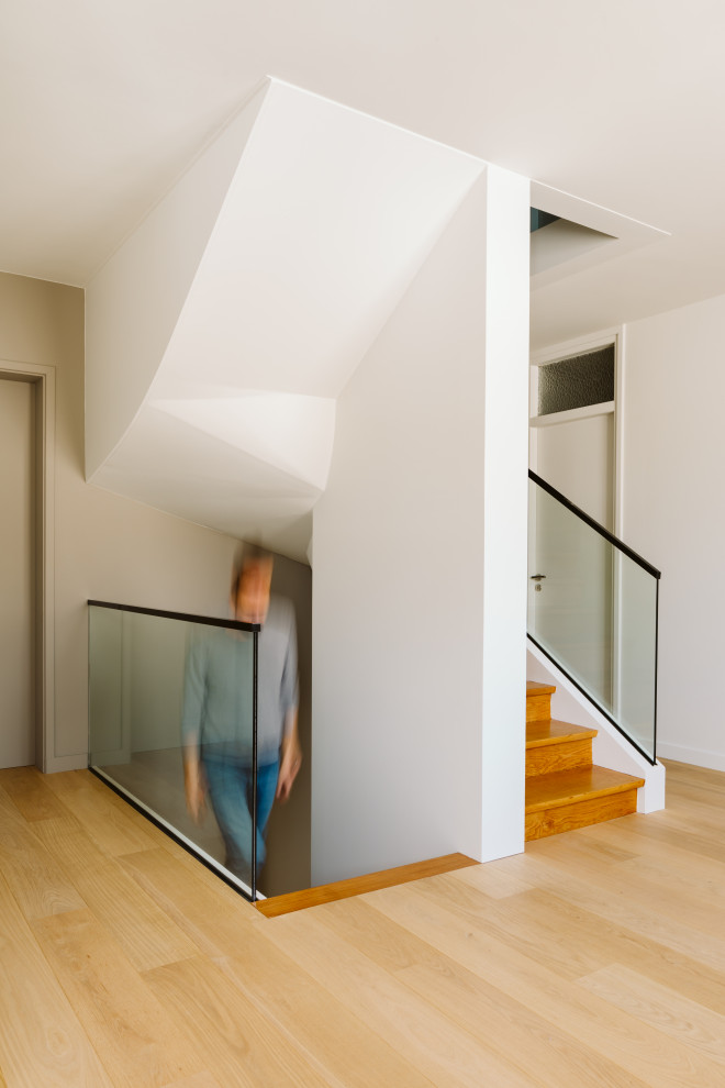 Exemple d'un escalier tendance en U de taille moyenne avec des marches en bois, des contremarches en bois et un garde-corps en verre.