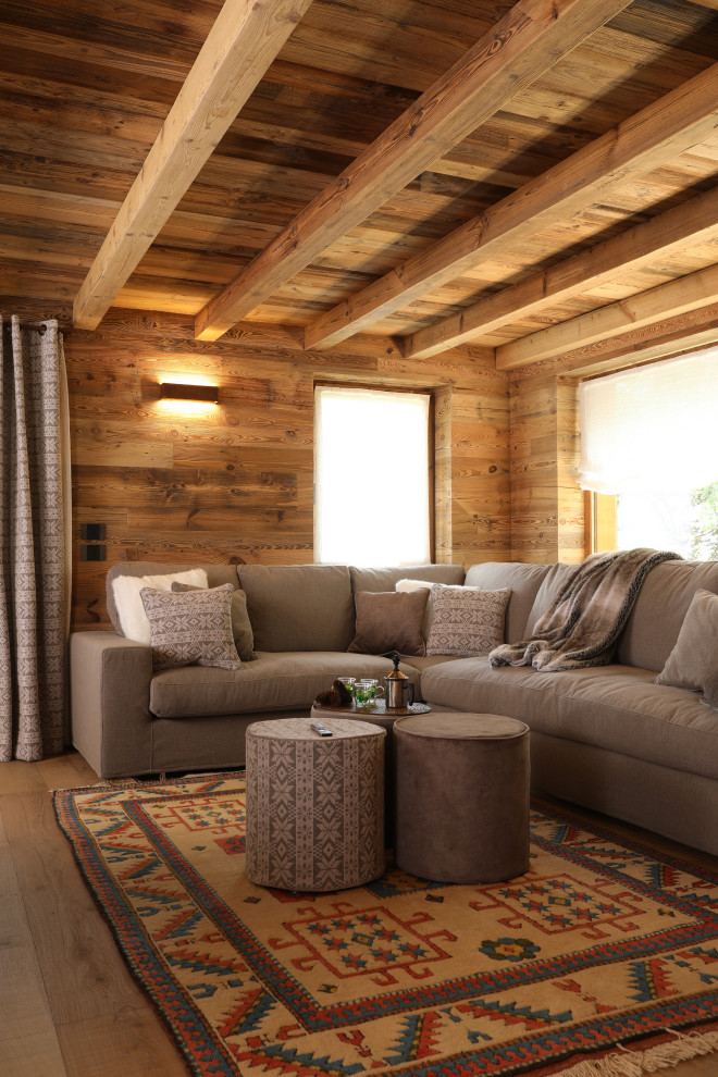 На фото: гостиная комната в стиле рустика с коричневыми стенами, паркетным полом среднего тона, коричневым полом, балками на потолке, деревянным потолком и деревянными стенами с