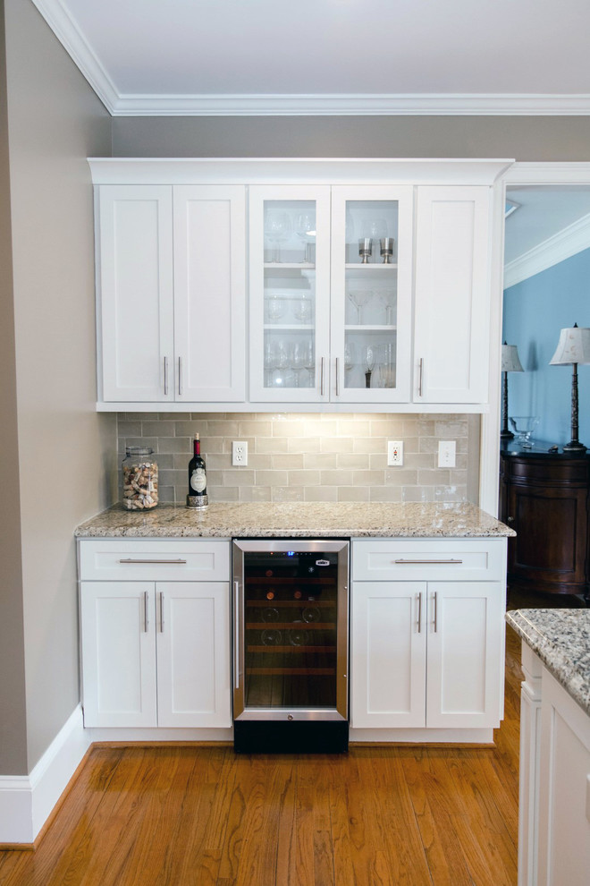 Photo of a mid-sized transitional l-shaped eat-in kitchen in Atlanta with a single-bowl sink, shaker cabinets, white cabinets, granite benchtops, beige splashback, stone tile splashback, stainless steel appliances, medium hardwood floors and with island.