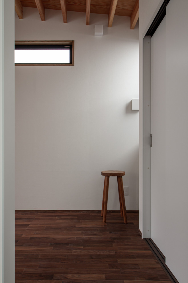 На фото: маленький коридор в восточном стиле с белыми стенами, темным паркетным полом, коричневым полом, балками на потолке и обоями на стенах для на участке и в саду с