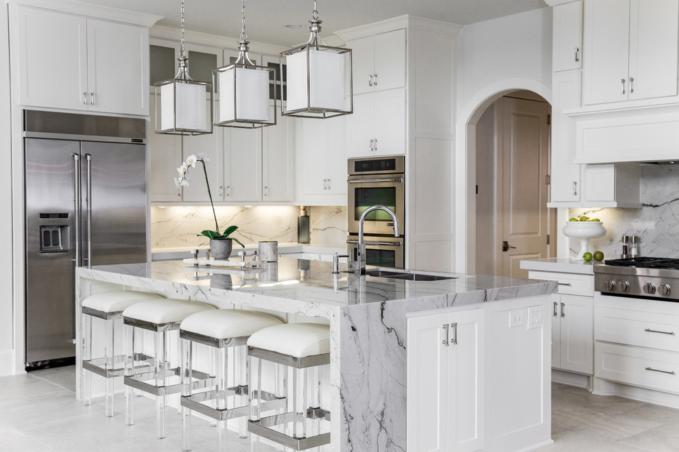 This is an example of a transitional l-shaped kitchen in Houston with an undermount sink, shaker cabinets, white cabinets, stainless steel appliances, with island, grey floor and grey benchtop.