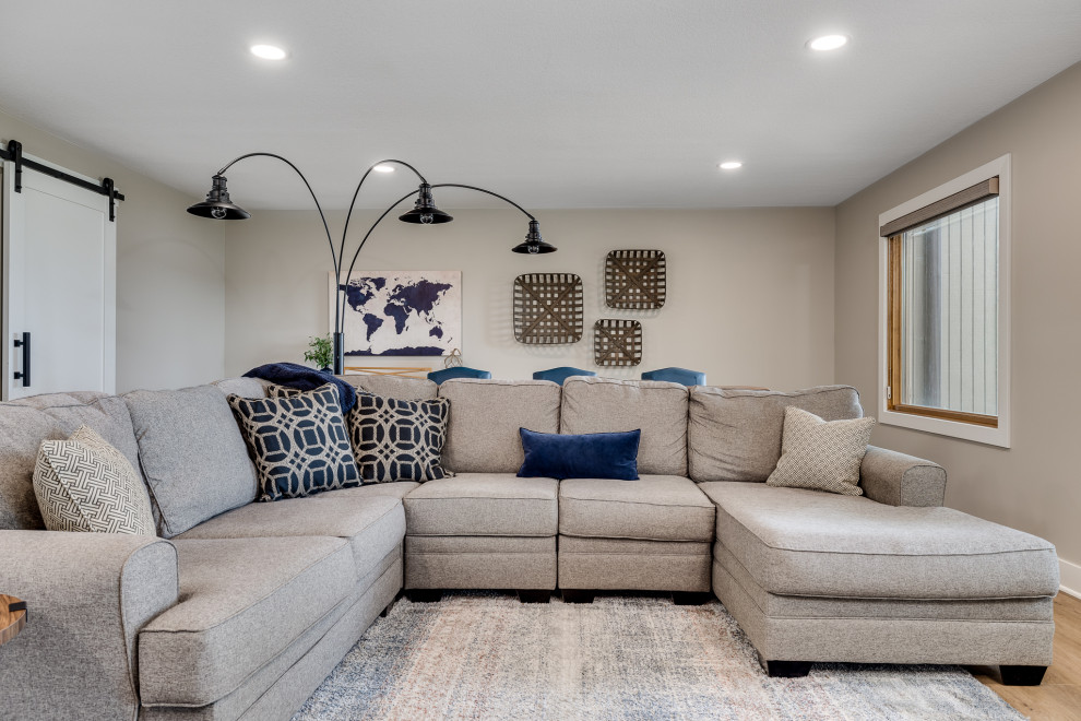 This is an example of a large open concept family room in Other with beige walls, vinyl floors, a standard fireplace, a brick fireplace surround, a wall-mounted tv and brown floor.