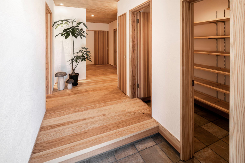 Medium tone wood floor and wood ceiling entryway photo in Fukuoka with white walls