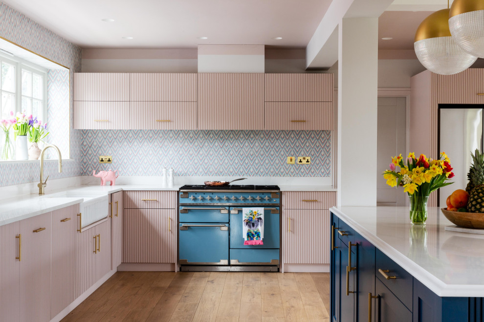 This is an example of a large eclectic eat-in kitchen in Hampshire with a farmhouse sink, pink cabinets and with island.