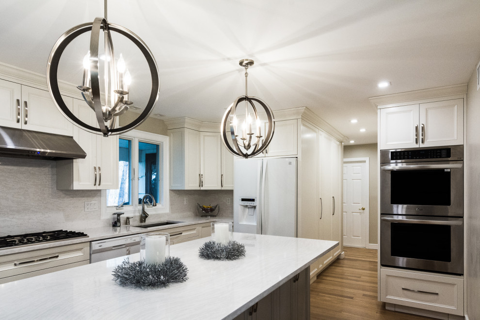 Inspiration for a large transitional l-shaped medium tone wood floor and brown floor eat-in kitchen remodel in New York with an undermount sink, shaker cabinets, white cabinets, quartzite countertops, gray backsplash, stone slab backsplash, stainless steel appliances, an island and gray countertops