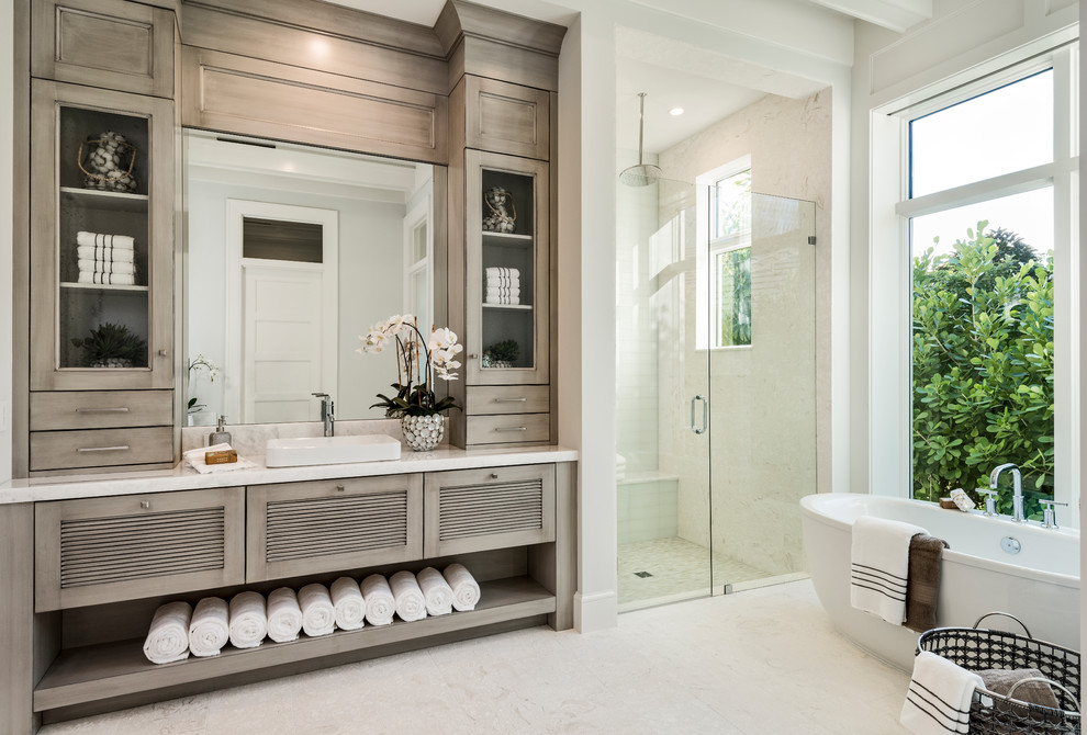 Inspiration for a transitional 3/4 bathroom in Other with louvered cabinets, grey cabinets, a freestanding tub, an alcove shower, beige tile, white walls, a vessel sink, beige floor and a hinged shower door.