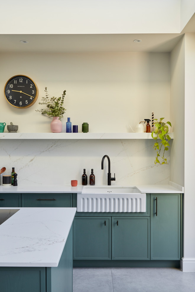 This is an example of a medium sized contemporary single-wall kitchen/diner in London with recessed-panel cabinets, white splashback, engineered quartz splashback, an island and white worktops.