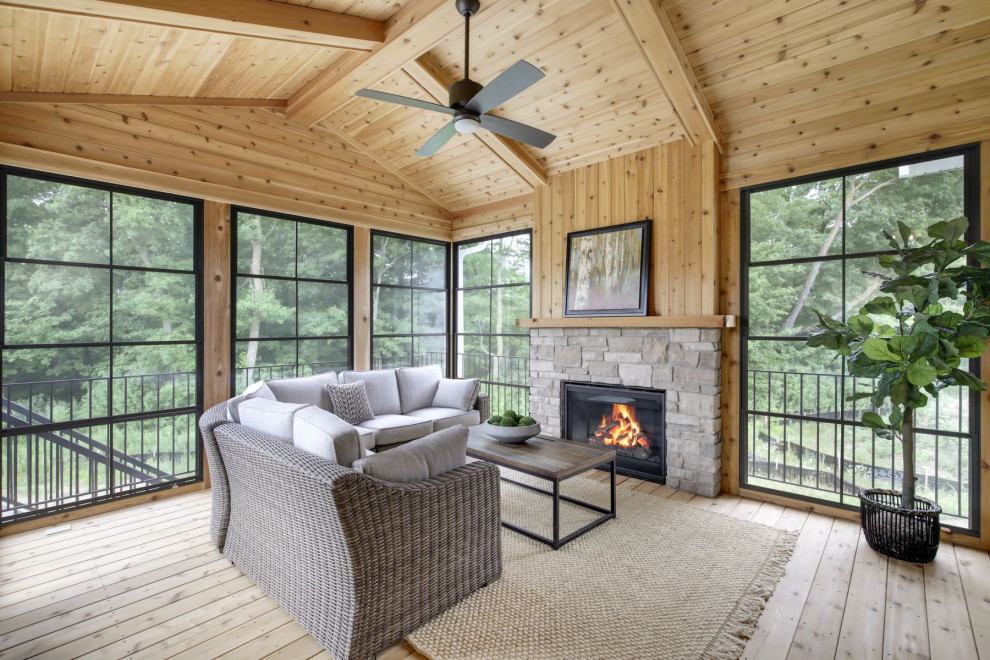 Photo of a transitional sunroom in Minneapolis with light hardwood floors, a standard fireplace, a stone fireplace surround, a standard ceiling and beige floor.