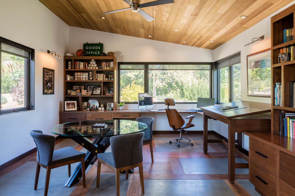 Design ideas for a mid-sized modern home office in Orange County with white walls, concrete floors, a built-in desk and grey floor.