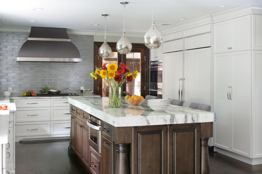 Inspiration for a mid-sized transitional u-shaped eat-in kitchen in New York with shaker cabinets, white cabinets, grey splashback, subway tile splashback, panelled appliances, dark hardwood floors, with island, a farmhouse sink, marble benchtops and grey floor.