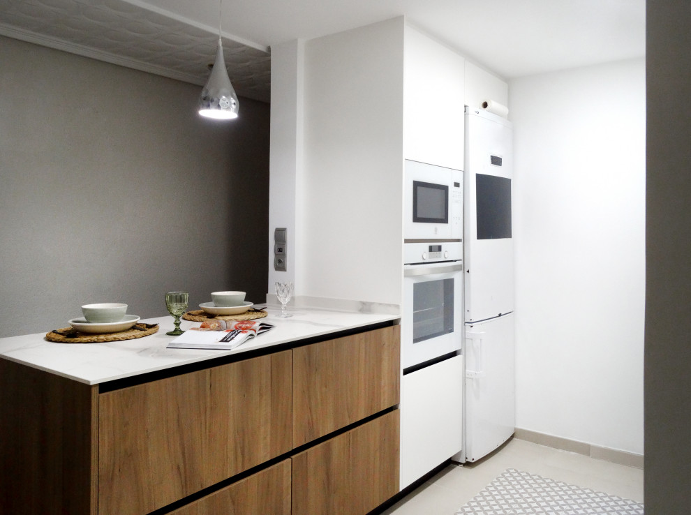 Bild på ett litet funkis vit vitt kök med öppen planlösning, med en undermonterad diskho, släta luckor, vita skåp, vitt stänkskydd och en halv köksö