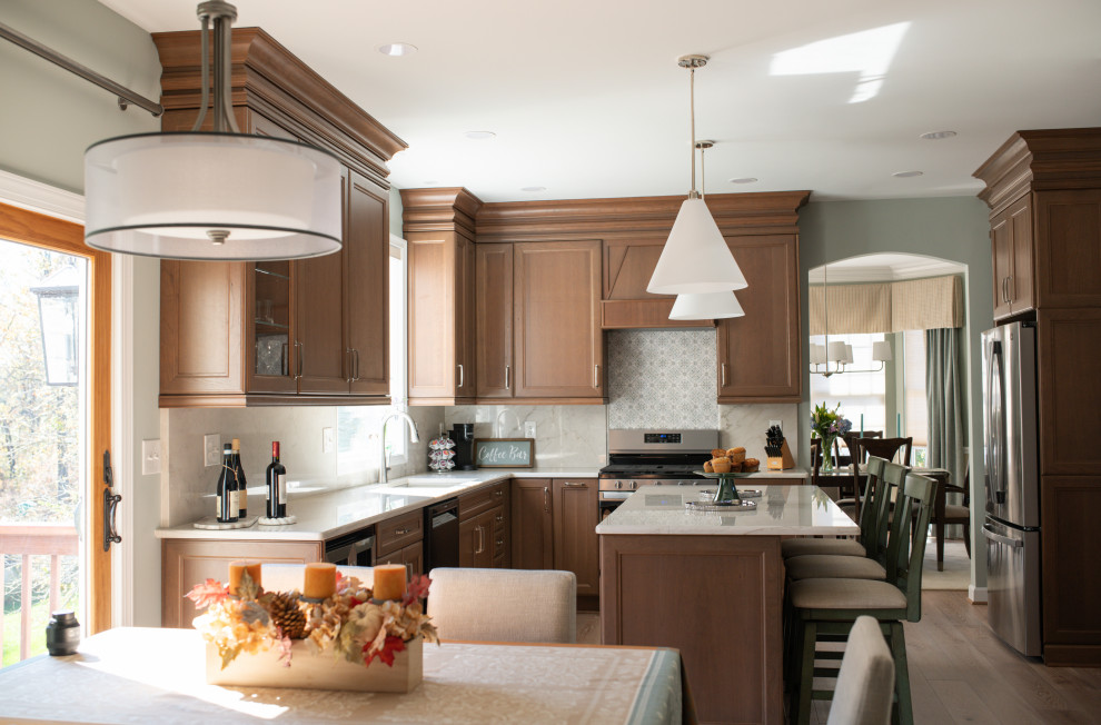 Example of a mid-sized beach style u-shaped light wood floor eat-in kitchen design in Baltimore with recessed-panel cabinets, medium tone wood cabinets, quartzite countertops, stainless steel appliances, an island and white countertops