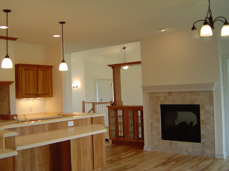 Inspiration for a mid-sized transitional l-shaped light wood floor eat-in kitchen remodel with a double-bowl sink, raised-panel cabinets, medium tone wood cabinets, solid surface countertops, stainless steel appliances and an island