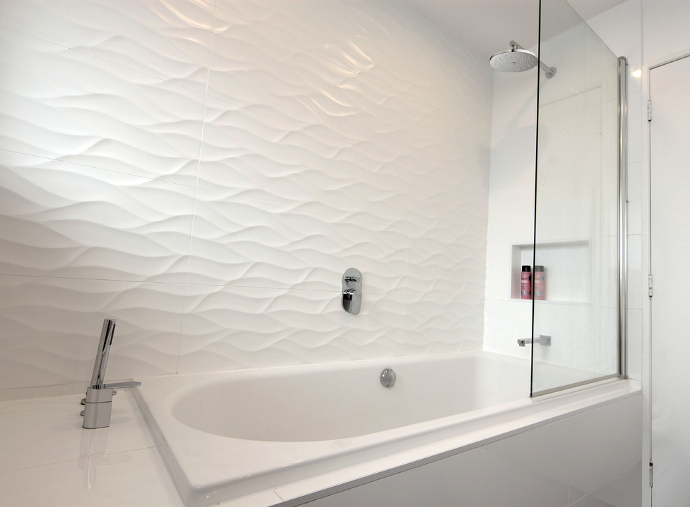 Inspiration for a mid-sized modern bathroom in Auckland with flat-panel cabinets, white cabinets, a drop-in tub, a shower/bathtub combo, a two-piece toilet, white tile, porcelain tile, white walls, porcelain floors, a drop-in sink, engineered quartz benchtops, brown floor and a hinged shower door.