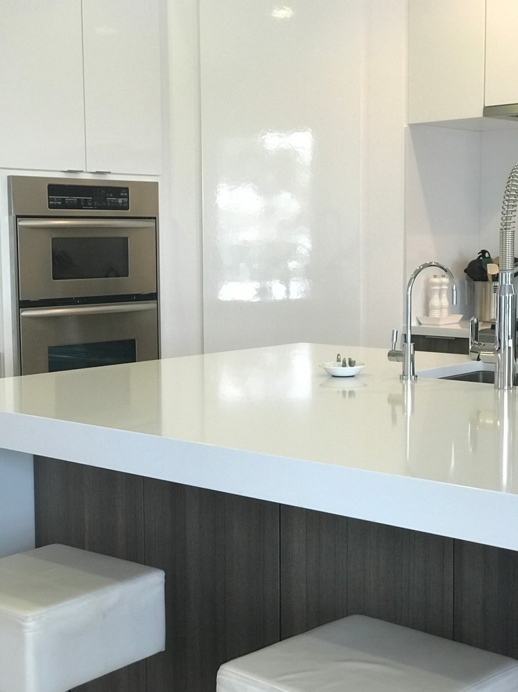 Photo of a mid-sized contemporary l-shaped eat-in kitchen in Miami with an undermount sink, flat-panel cabinets, white cabinets, quartzite benchtops, white splashback, stainless steel appliances and with island.