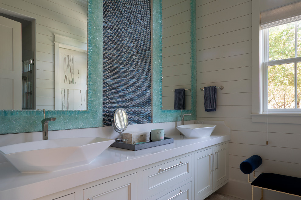 Inspiration for a large beach style 3/4 bathroom in Other with recessed-panel cabinets, white cabinets, an alcove tub, a one-piece toilet, blue tile, mosaic tile, white walls, ceramic floors, a drop-in sink, beige floor, a hinged shower door, white benchtops, a double vanity, a floating vanity, wood and planked wall panelling.