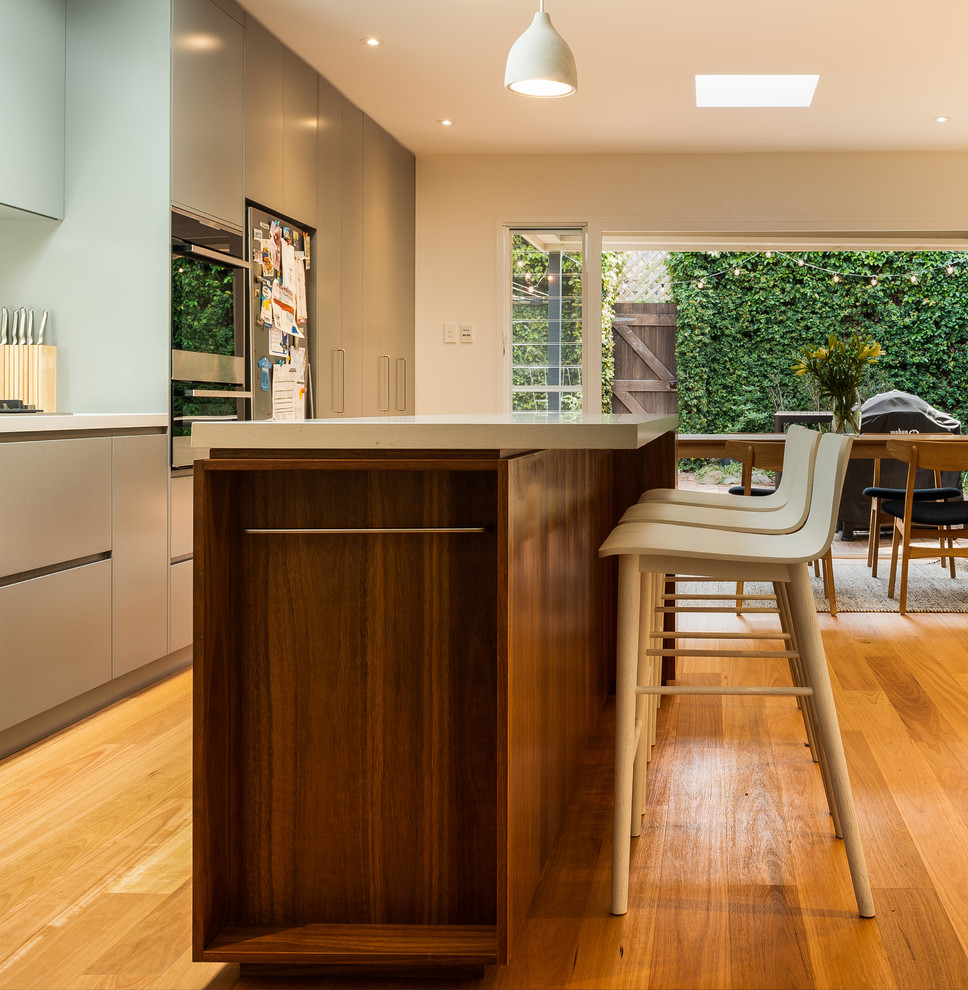Photo of a mid-sized contemporary kitchen in Sydney with an undermount sink, grey cabinets, white splashback, ceramic splashback, medium hardwood floors, with island and grey benchtop.