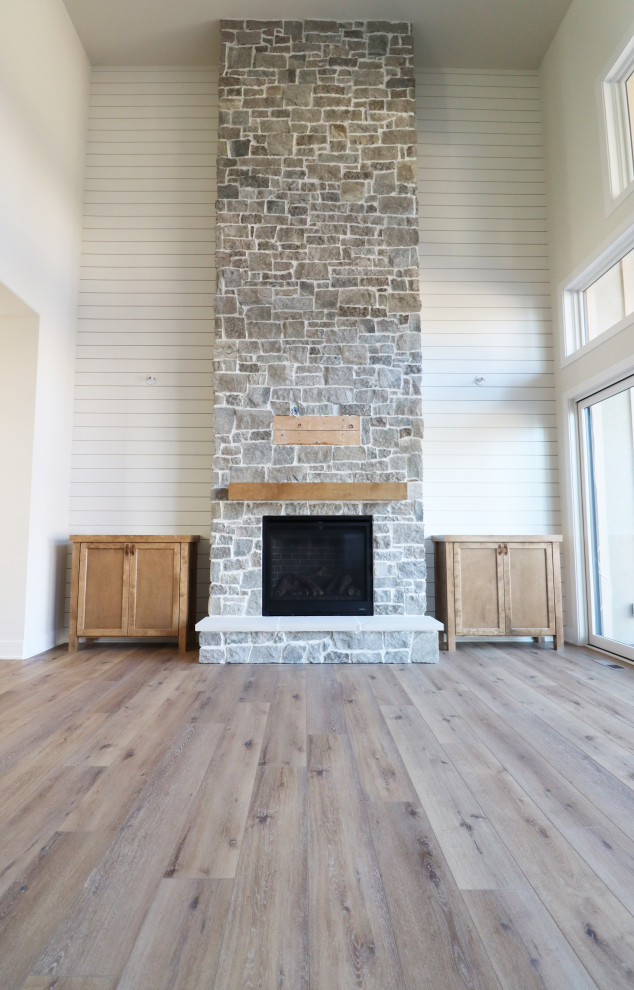 Offenes Klassisches Wohnzimmer mit Kamin, Kaminumrandung aus Stein, TV-Wand und Holzdielenwänden in Omaha