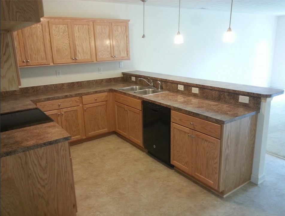 Inspiration for an u-shaped ceramic tile eat-in kitchen remodel with a drop-in sink, recessed-panel cabinets, light wood cabinets, laminate countertops and black appliances