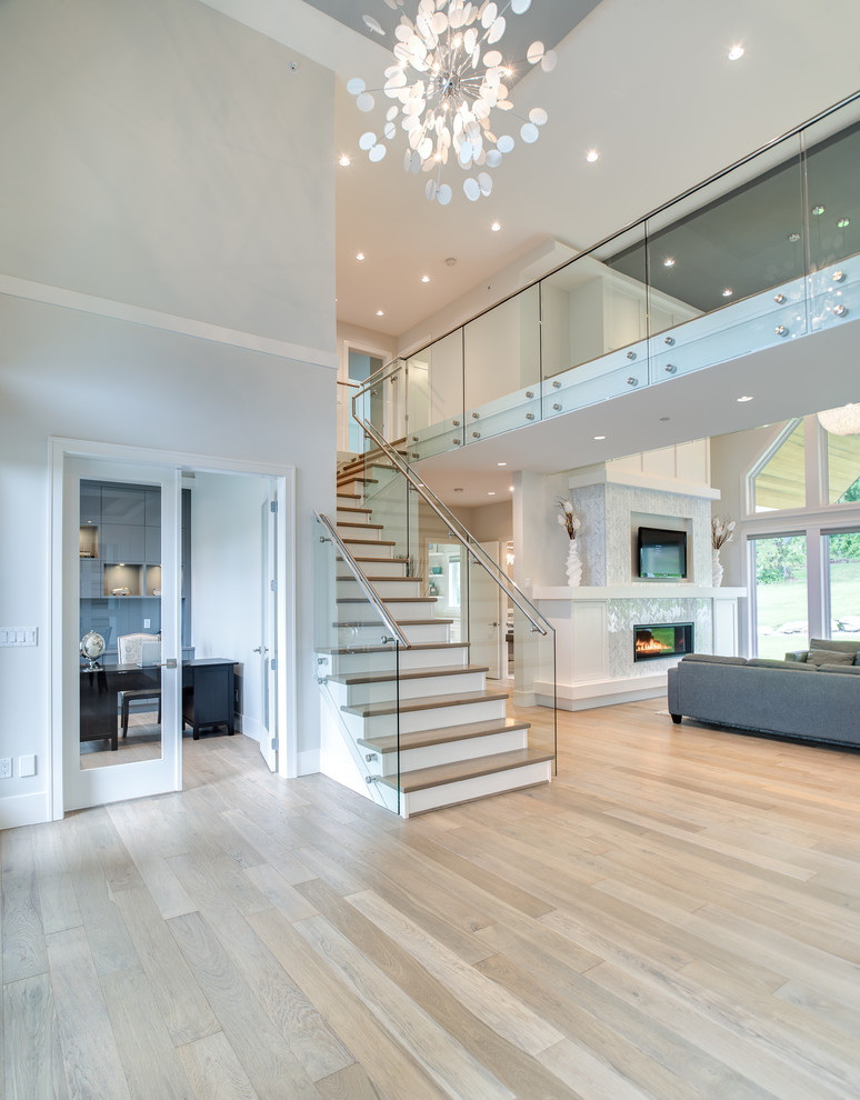 This is an example of a large transitional wood l-shaped staircase in Vancouver with glass railing.