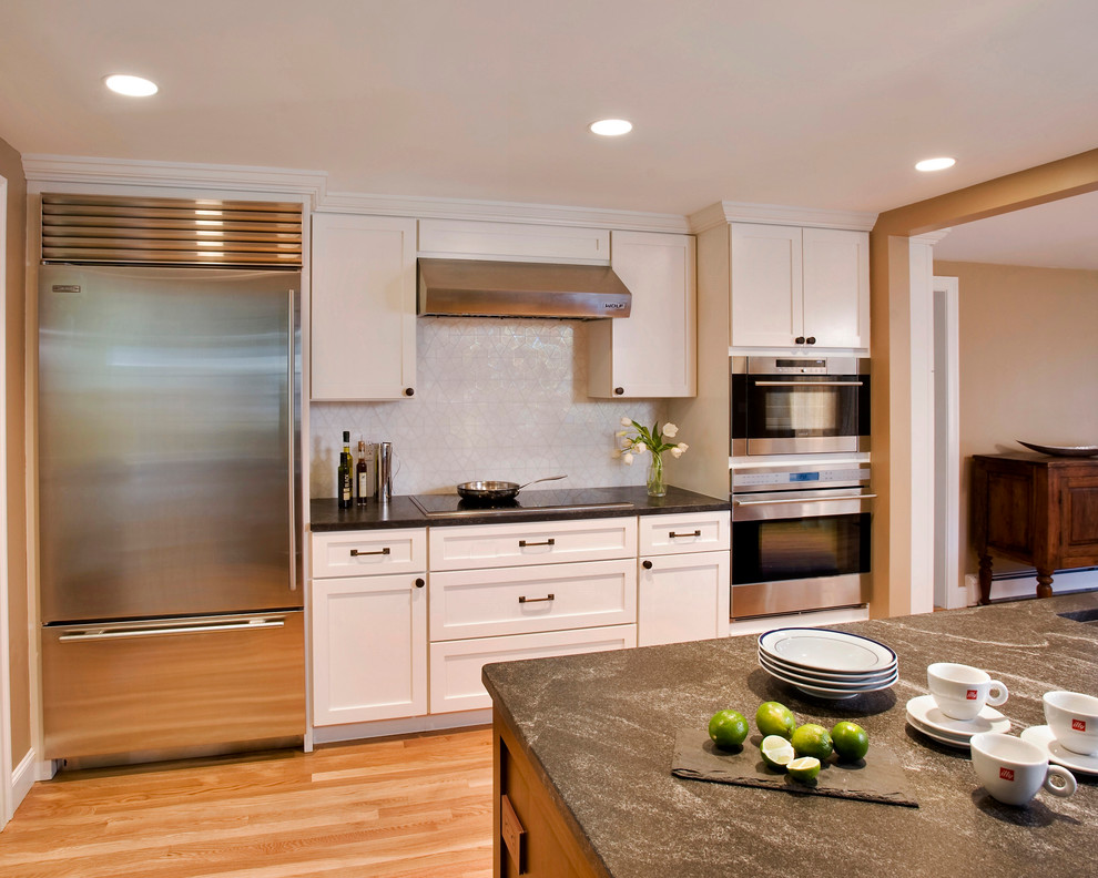 Example of a transitional galley eat-in kitchen design in Boston with an undermount sink, shaker cabinets, white cabinets, granite countertops, white backsplash and stainless steel appliances