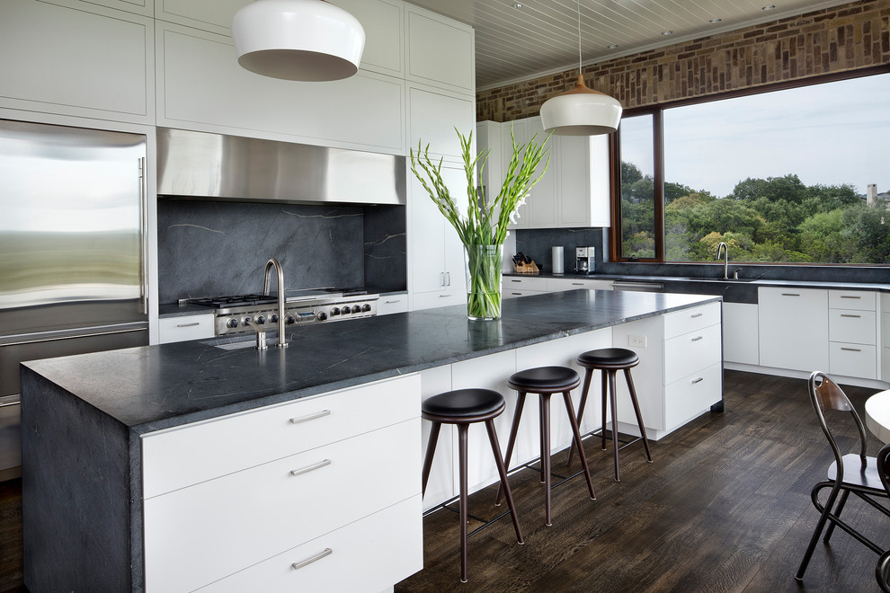 This is an example of a large contemporary single-wall eat-in kitchen in Austin with an undermount sink, beaded inset cabinets, white cabinets, soapstone benchtops, stone slab splashback, stainless steel appliances, dark hardwood floors and with island.