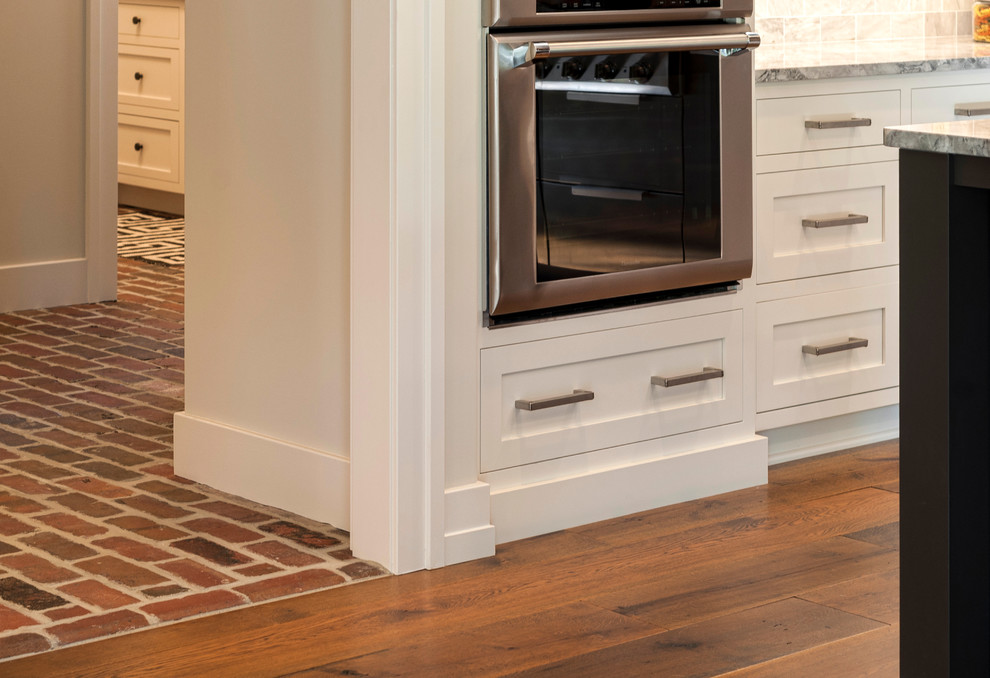 Inspiration for a traditional eat-in kitchen with stainless steel appliances, medium hardwood floors and brown floor.
