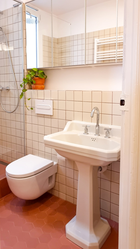 Exempel på ett litet eklektiskt badrum, med en toalettstol med hel cisternkåpa, keramikplattor, beige väggar, klinkergolv i terrakotta, ett piedestal handfat, rött golv och dusch med gångjärnsdörr