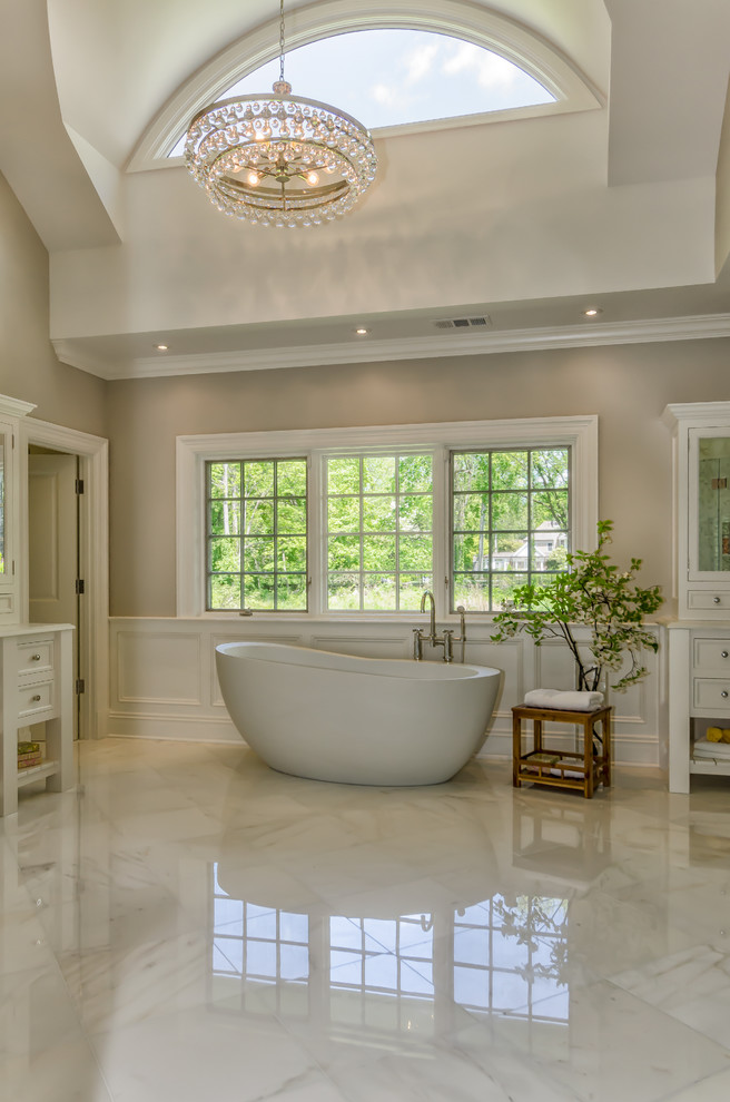 This is an example of a traditional master bathroom in New York with recessed-panel cabinets, white cabinets, a freestanding tub, white tile and grey walls.