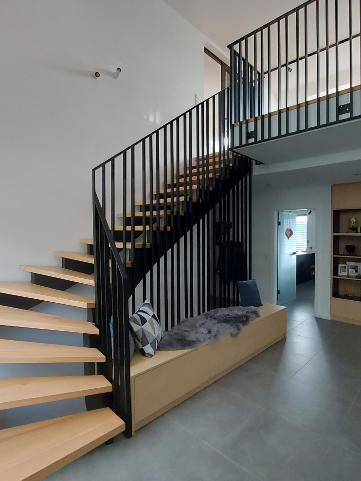Design ideas for a large contemporary wood curved metal railing staircase in Frankfurt with open risers and wallpapered walls.