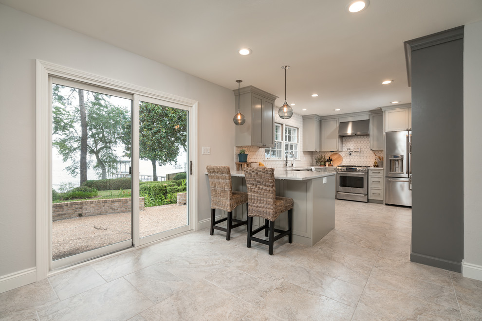 Inspiration for a large transitional u-shaped porcelain tile enclosed kitchen remodel with an undermount sink, shaker cabinets, gray cabinets, quartz countertops, white backsplash, ceramic backsplash, stainless steel appliances and a peninsula