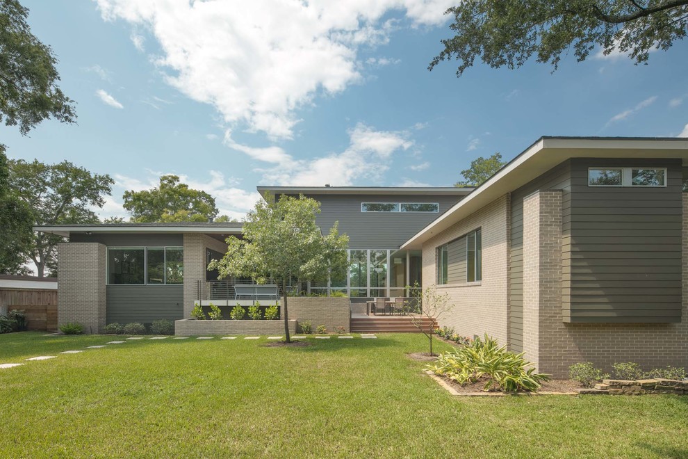 Photo of a mid-sized midcentury two-storey brick grey house exterior in Houston with a flat roof.