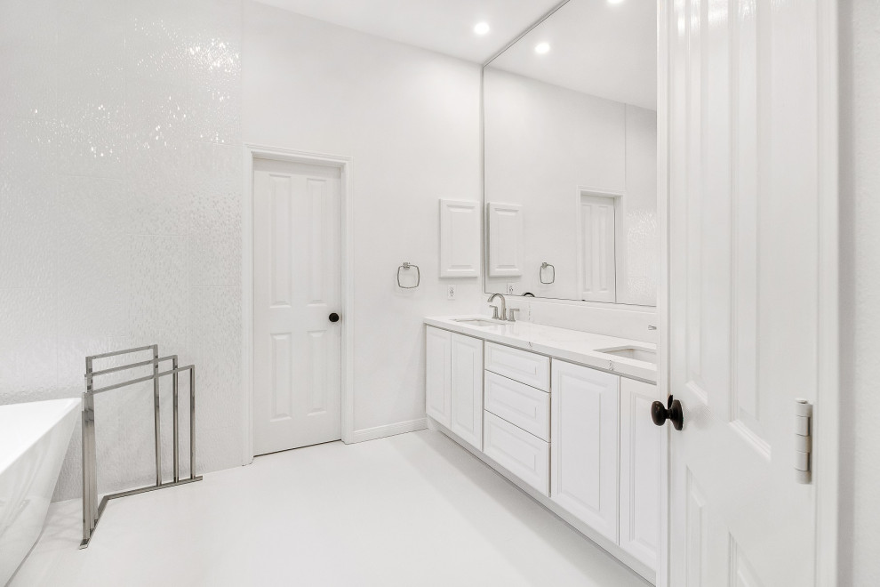 Photo of a mid-sized contemporary master bathroom in Houston with raised-panel cabinets, white cabinets, a freestanding tub, a corner shower, a two-piece toilet, white tile, ceramic tile, white walls, ceramic floors, an undermount sink, engineered quartz benchtops, white floor, a hinged shower door and white benchtops.