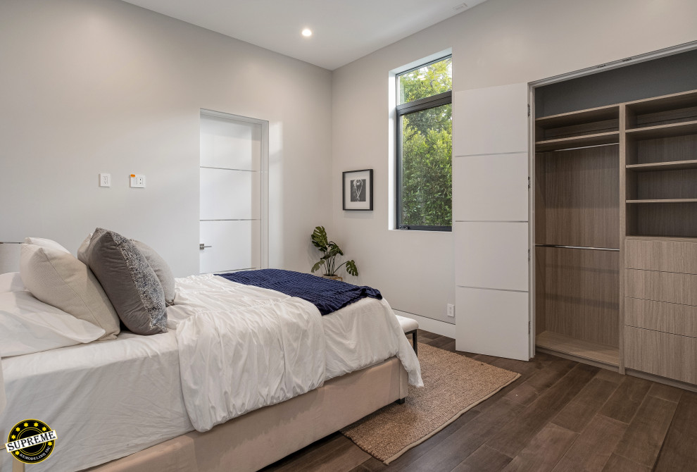 Inspiration for a mid-sized modern guest bedroom in Los Angeles with white walls, medium hardwood floors and brown floor.