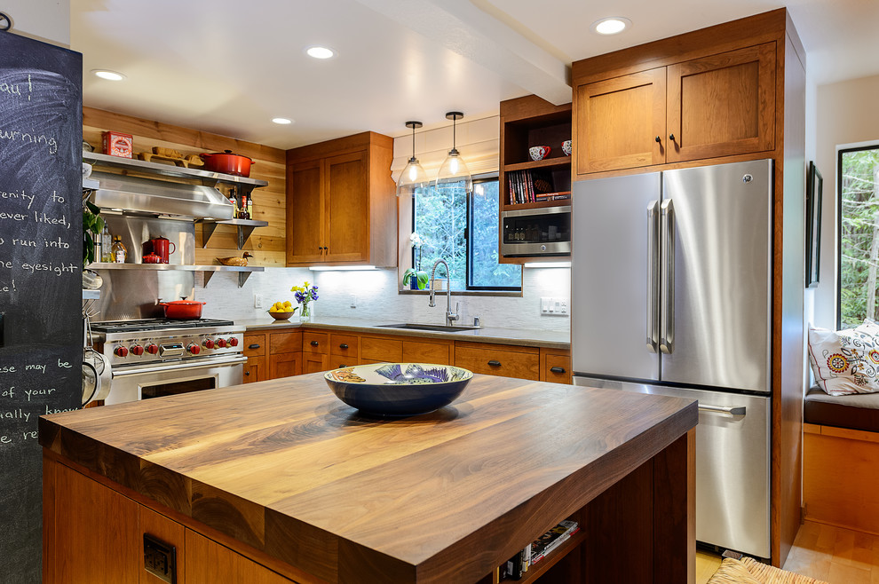 Photo of a mid-sized country l-shaped eat-in kitchen in San Francisco with shaker cabinets, with island, an undermount sink, medium wood cabinets, quartz benchtops, white splashback, stone tile splashback, stainless steel appliances and light hardwood floors.