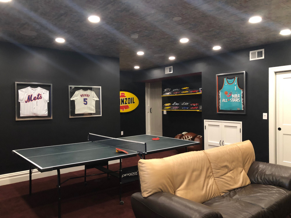 Photo of a large contemporary look-out basement in New York with black walls, carpet and red floor.