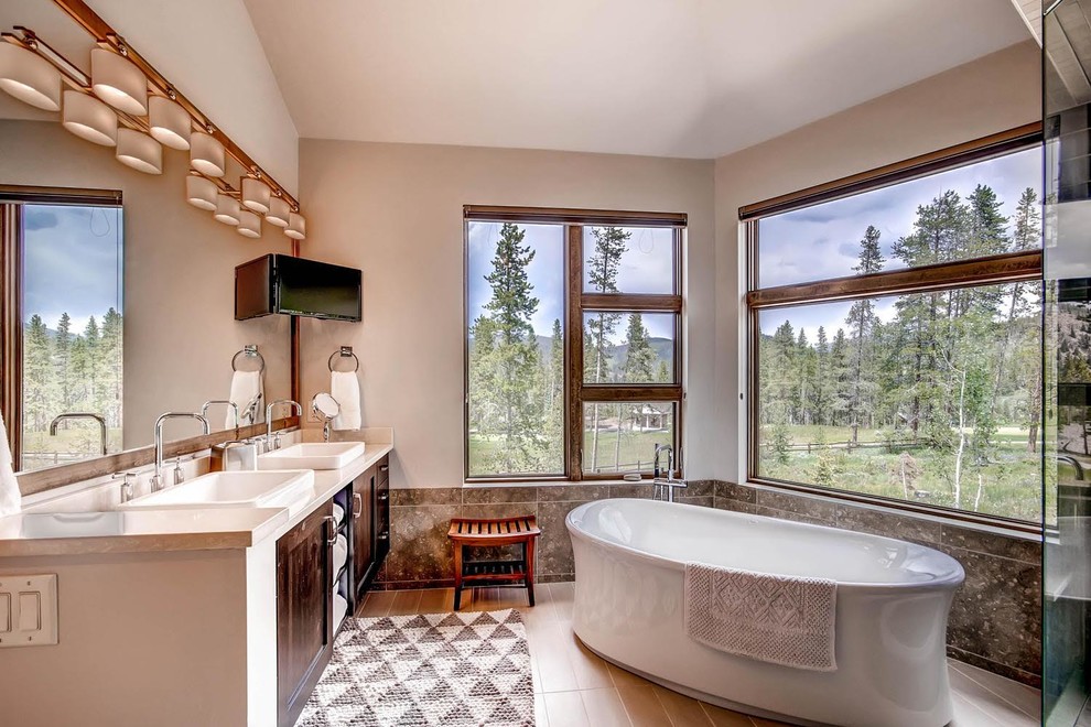 This is an example of a large country master bathroom in Denver with shaker cabinets, medium wood cabinets, a freestanding tub, brown tile, grey walls, a vessel sink, a corner shower, cement tile, porcelain floors, quartzite benchtops, brown floor and a hinged shower door.