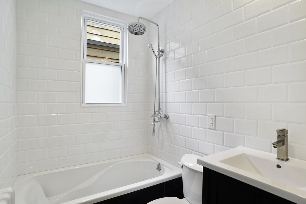 Mid-sized midcentury kids bathroom in New York with flat-panel cabinets, black cabinets, a drop-in tub, an alcove shower, a two-piece toilet, white tile, ceramic tile, white walls, porcelain floors, an undermount sink, solid surface benchtops, black floor, a shower curtain and white benchtops.