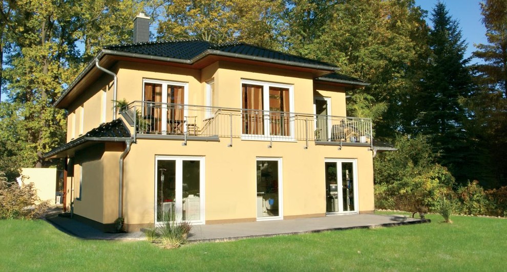 Großes, Zweistöckiges Mediterranes Haus mit Putzfassade, gelber Fassadenfarbe und Walmdach in Berlin